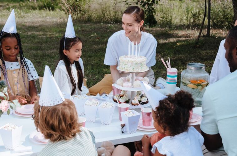 Children enjoying a lively outdoor birthday party with cake and decorations.