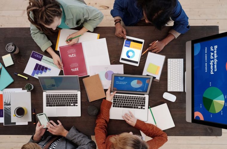 A diverse team collaborating on digital marketing strategies at a desk, using laptops and tablets.